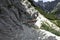 A girl crosses a wooden bridge suspended in the void on a bumpy and dangerous path during a trek in the Italian Alps.