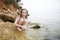 Girl Crouching On Rock By Sea