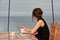 A girl in a cruise liner restaurant is eating a cake and looking out into the ocean