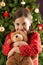 Girl Cuddling Teddy In Front Of Christmas Tree