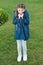 Girl cute face braided hair posing coat in spring park. Clothing for spring walks. Little fashion model. Clothes and