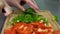 Girl cuts red and green fresh peppers on a wooden board in her kitchen close-up of hands. woman prepares a dish