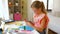 Girl cutting color paper with scissors at home