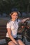 Girl cyclist rests in the park on a bench. Athlete teenager resting in the park at sunset