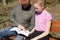 Girl with dad reads a book and smiles on a park bench