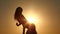 Girl is dancing belly dancing against the beautiful sunset on the beach. Silhouettes