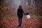 Girl in dark clothing among autumn foggy forest, with two balloons, black and white. Concept of choice, good and evil