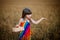 A girl with dark hair sits in a field that looks like wheat