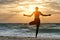 Girl at dawn practicing yoga at the seashore, silhouette