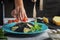 A girl decorates a dish of black spaghetti with cherry tomatoes. Unusual cuttlefish ink pasta. A wholesome light dinner