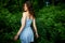 A girl in a delicate blue dress walks along a path on the top of a mountain near the river