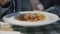 A girl in a denim jacket eats Italian pasta with beef mitbols and tomato sauce.