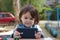 girl in a denim jacket holds in her hands and looks into the smartphone while sitting at a table on the playground