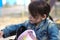 A girl in a denim jacket with a tail looking in a backpack on the playground