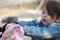 A girl in a denim jacket with a tail looking in a backpack on the playground