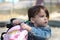 A girl in a denim jacket with a tail looking in a backpack on the playground