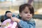 A girl in a denim jacket with a tail looking in a backpack on the playground