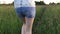 Girl in denim shorts goes through the long grass