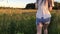 Girl in denim shorts goes through the long grass