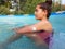 A girl with diabetes is sitting in the pool. On the left arm is the white sensor for continuous  glucose monitoring in blood - CGM