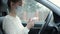 Girl disinfects her hands with an antibacterial wipe after a meeting, sitting in a car in a medical mask