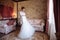 The girl is dizzy in her cozy room trying on a wedding dress. The bride admires her attire for the wedding day.