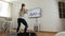 The girl does exercises while watching a program on TV at home. A young woman in sportswear, athletic build, plays