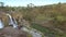 Girl does yoga on rocky land against waterfall streaming from cliff