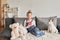 Girl and dog laying on couch in headphones, listening to music with her smarthphone. Little girl watching cartoons on her phone.