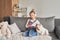 Girl and dog laying on couch in headphones, listening to music with her smarthphone. Little girl watching cartoons on her phone.