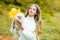 Girl with doggy on fall maple leaf outdoors. Emotional support. Beautiful autumn time in nature.