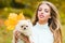 Girl with doggy on fall maple leaf outdoors. Emotional support. Beautiful autumn time in nature.