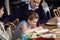 A girl doing her homework at the kitchen table with her parents being around