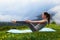 Girl doing yoga exercise balance on lawn in mountains