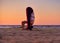 Girl doing yoga by the sea at sunset