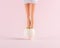 Girl doll legs in cracked Easter egg on pastel pink background. Easter minimal concept. Creative Happy Easter or spring layout