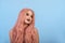 Girl with a doll with pink hair wig. Blue background.