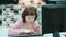 Girl with Down syndrome sitting at a computer at home and typing text.