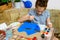 A girl drawing blue gouache cardboard, artistic creation at home, makes creative artwork