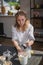 Girl draws on a clay bowl. Female potter works in her studio glazing ceramic pot.