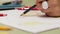 Girl draws left-handed with black pencil on paper, detailed view in slowmotion