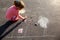 Girl draws painting sun house chalk on asphalt