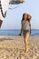 a girl with a dreadlocked hairstyle poses on the beach near a ship