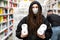 Girl with dreadlocks in a white medical mask buys toilet paper in a supermarket