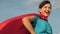 Girl dreams of becoming a superhero. beautiful girl superhero standing on field in red cloak, cloak fluttering in wind