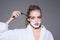 Girl on dreamy face wears bathrobe, grey background. Lady play with sharp blade of straight razor. Woman with face