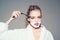Girl on dreamy face wears bathrobe, grey background. Lady play with sharp blade of straight razor. Woman with face