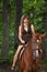 Girl in dress and brown horse portrait in forest