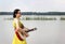 A girl in a dress plays the guitar standing barefoot in the water of a lake in nature