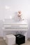 Girl in dress sitting on white piano in room